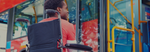 Man in wheelchair waiting at a bus stop.