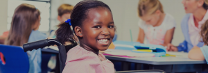 A girl sitting in a wheelchair in her classroom.