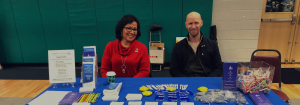 Two dLCV volunteers, sitting at a table, smiling at the camera.