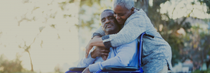 Wife hugging her husband in a wheelchair.