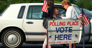 Two Polling Place workers assisting an individual with disabilities with curbside voting.