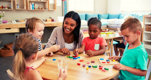 A teacher sitting at a table surrounded by four students.