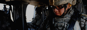 Soldier and a black dog cuddling inside of a helicopter.