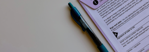 A blank absentee ballot with a green pen beside it.
