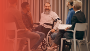 Happy Senior man sitting in a wheelchair and talking to a group of people sitting in a circle.