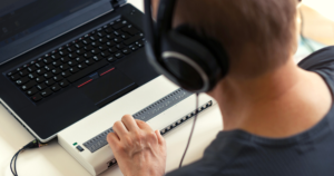 A child using an accessible keyboard. He has headphones on as well.