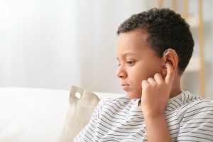 Little African-American boy with hearing aid at home