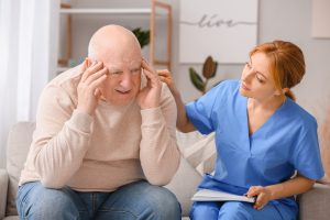 Elderly man suffering from mental disability and caregiver in nursing home