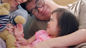 Happy family with mother, father and disabled daughter spending time together at home..