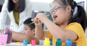 Disabled kids classroom, children having fun during study at school, kids learning together, schoolgirl concentrate painting in art classroom
