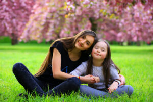 Happy beautiful young woman with girl in blossom park with trees