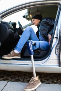 Young man with prosthetic leg driving car.