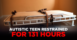 A narrow institutional bed, fitted with leather restraint straps attached to the frame.A narrow institutional bed, fitted with leather restraint straps attached to the frame.